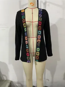 Detail of black ribbed knit cardigan featuring colorful crochet flower appliques