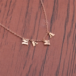 Rose gold MAMA letter pendant necklace in stainless steel on a dark wood background
