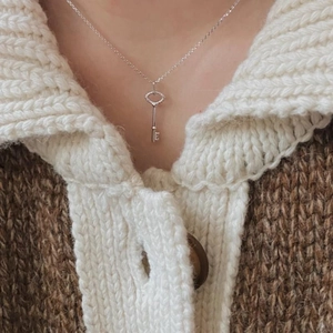 Close-up of 925 sterling silver key pendant necklace worn on a cozy knitted sweater