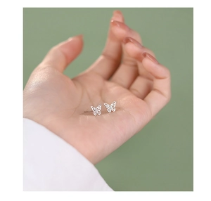 Macro shot of S925 sterling silver butterfly earrings held in hand for scale