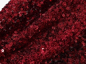 Macro view of sparkling red sequin fabric texture on V-neck dress detail