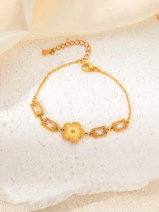 Detail of gold daisy flower bracelet with clear zircon stones on textured white stone