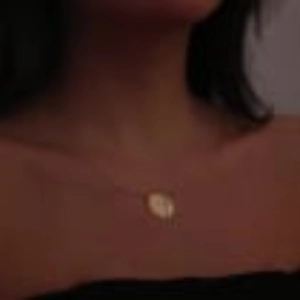 Close-up of golden sun and moon pendant necklace worn on neck for minimalist style