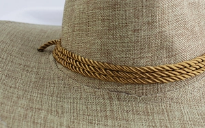 Détail de la texture du chapeau tissé beige avec une corde décorative torsadée à brins