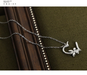 Macro detail of silver necklace with floral pendant over vintage dark fabric background