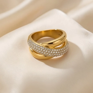 Detail of gold-plated geometric ring with intertwined rows of sparkling cubic zirconia