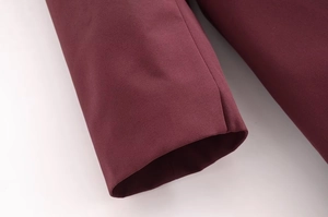 Détail rapproché du poignet d'un trench-coat bordeaux avec des coutures de qualité