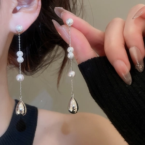 Gros plan de boucles d'oreilles vintage avec perles blanches et pendentifs en forme de goutte