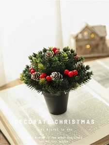 Close-up of mini Christmas tree with snowy pine cones, red berries and black pot