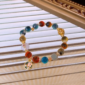 Close-up of vintage beaded bracelet with agate, pearls, and gold flower pendant detail