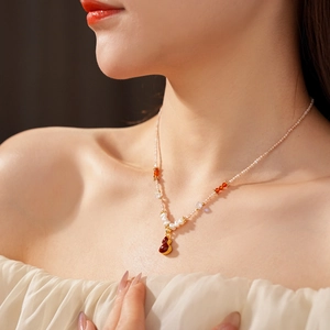 Detail of freshwater pearl necklace with red gourd pendant on a model's neck