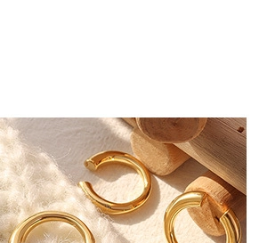 Detail view of polished 18K gold plated minimalist ear cuffs on white knit and wood