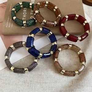 Set of six colorful geometric acrylic bracelets with gold glitter and metallic accents