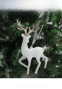 Close-up of white flocked reindeer ornament with golden antlers on a snowy tree