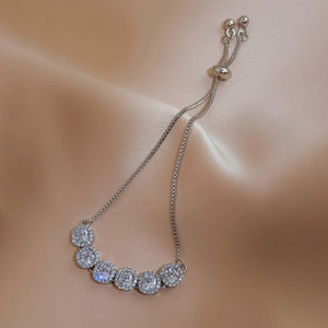 Detail of adjustable silver zircon bracelet with six round stones on pink satin backdrop