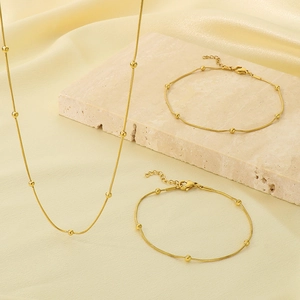 Détail de colliers et bracelets à billes dorées sur pierre texturée et soie douce