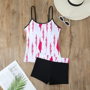 Flat lay of pink tie-dye tankini set with swim shorts on dark wooden background