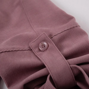 Detail of dusty pink corduroy fabric texture and matching four-hole button on the dress