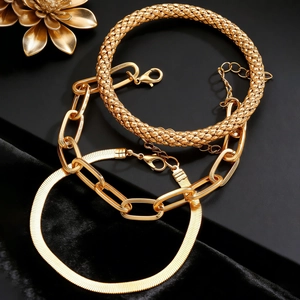 Close-up of gold-plated bracelet set featuring flat snake and braided textured chains