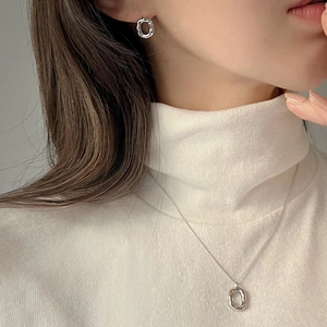 Close-up of irregular textured silver earrings and necklace on model with cream sweater