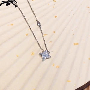 Macro detail of silver four-pointed star pendant necklace with cubic zirconia on a fan background