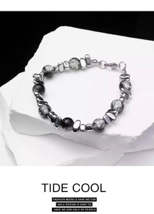 Close-up of beaded bracelet with black ink-pattern beads and irregular steel spacers