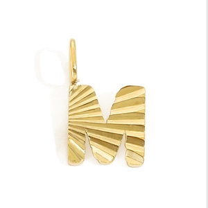 Close-up of golden letter M pendant with radial texture and polished metal finish