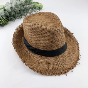 Detail of coffee brown straw fedora with black ribbon and frayed edges on white background
