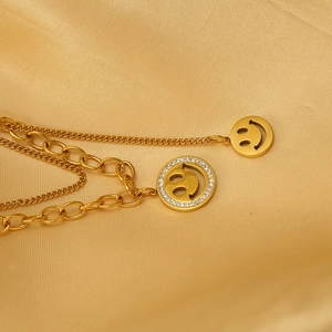 Collier multicouche doré avec pendentifs smiley en strass sur fond de satin brillant
