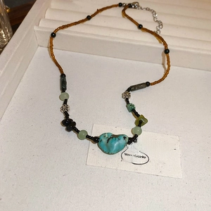 Detail view of vintage beaded necklace with green turquoise heart pendant and lobster clasp