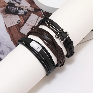 Close-up of multilayered leather bracelet set with silver guitar charm on a white stand