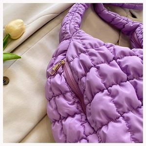 Macro shot of purple quilted puffy tote showing fabric texture and gold zipper detail