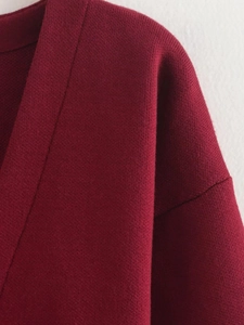 Gros plan des coutures d'épaule et de la maille fine sur un pull de couleur bordeaux