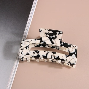 Modern acetate hair claw clip with black and white marble pattern on a split background