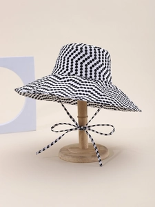 Detail of wide brim sun hat with classic black polka dots and decorative bow tie