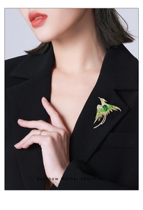 Macro view of phoenix brooch with green emerald stone on black blazer lapel