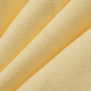 Macro shot of warm yellow wool fabric texture showing soft fiber detail on coat