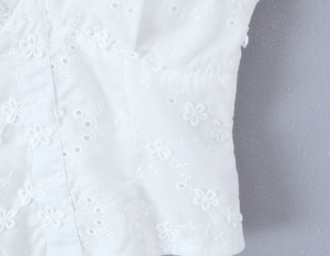 Primer plano del top blanco de verano con bordado floral intrincado y textura calada