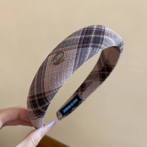 Detail of checkered fabric headband featuring a small metal Korea brand plate
