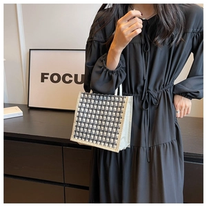 Mini houndstooth pattern tote bag held by a model in a minimalist indoor setting