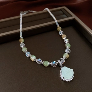 Detail of beaded necklace featuring a light green Buddha pendant with zircon inlay