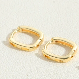 Detail of gold rectangular huggie earrings featuring geometric hollowed sides and smooth finish