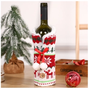Close-up of knitted Christmas wine bottle cover with reindeer motif and white pom pom bow