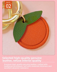 Close-up of orange-shaped leather keychain showing pebbled texture and gold ring