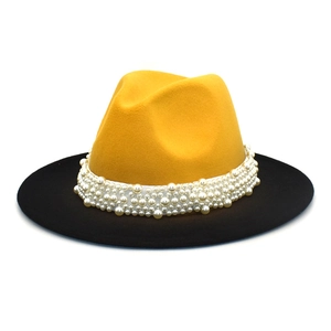 Detail of yellow and black two-tone fedora hat with elegant pearl embellishments