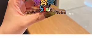 Detailed view of a brown hair claw clip featuring colorful smiling stars and Star text