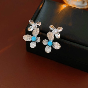 Macro shot of butterfly earrings with silver wings, blue beads and small white pearls