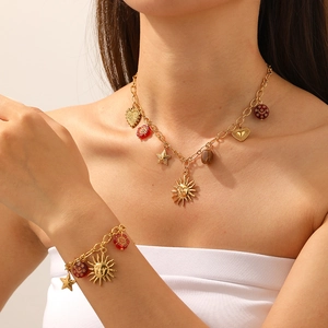 Détail d'un ensemble collier et bracelet doré vintage avec breloques soleil et cœur