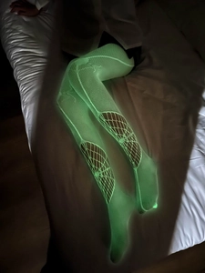 Bas résille vert fluo lumineux avec design déchiré montrés dans l'obscurité