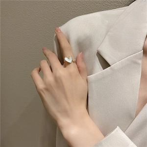Model wearing a gold heart open ring with white inlay and sparkling crystal stone